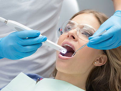 Woman undergoing dental treatment with a device inserted into her mouth.